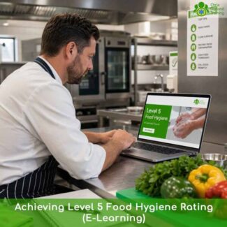 A chef in a professional kitchen sitting at a stainless steel counter and looking at a laptop displaying a "Level 5 Food Hygiene" e-learning course. Fresh vegetables are visible in the foreground.