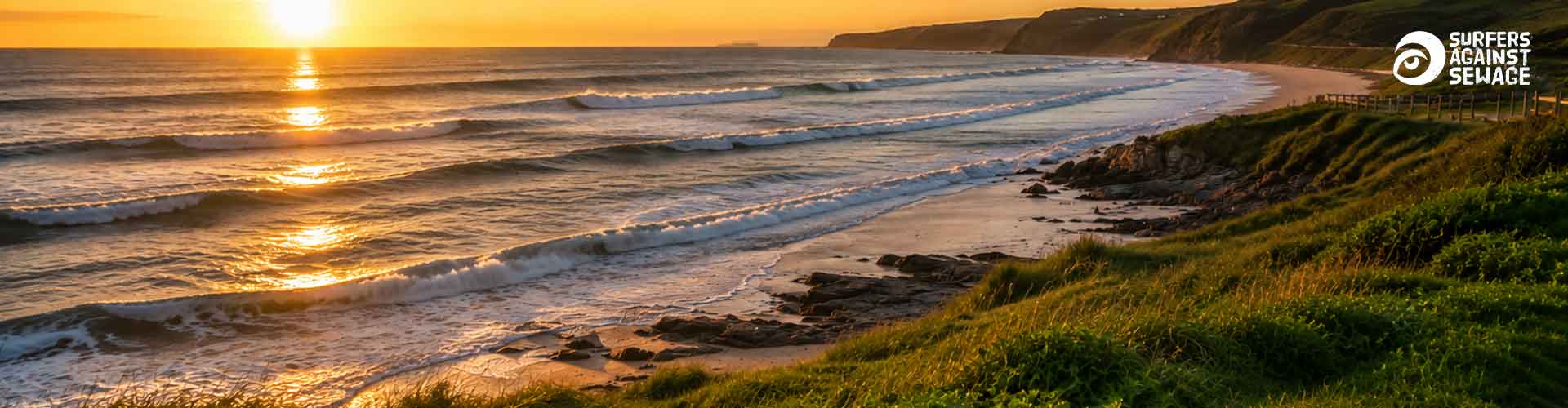 A scenic coastline with ocean waves rolling onto a sandy beach at sunset, featuring the Surfers Against Sewage charity logo.